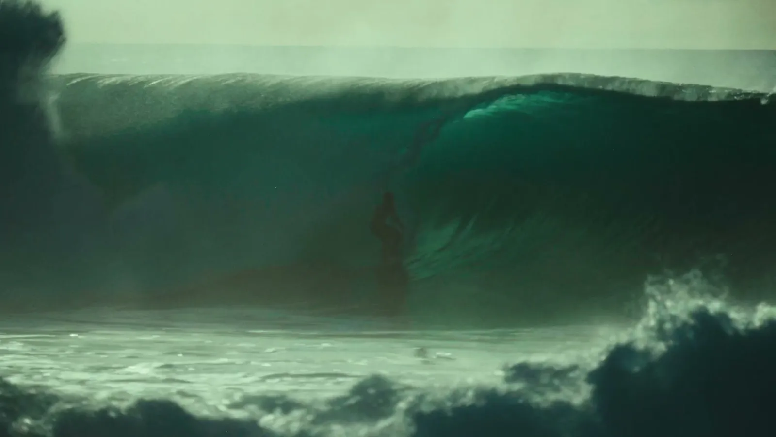 A surfer deep inside a teal barrel — the keeper