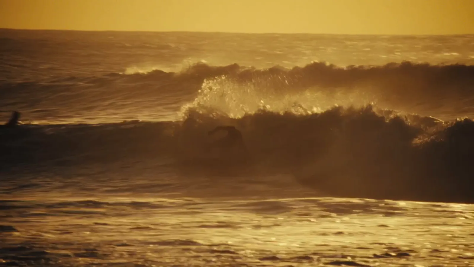 A golden wave breaking at sunset